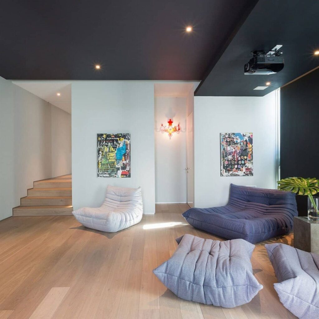 Black ceiling in a modern living room with light wood floors and lounge seating