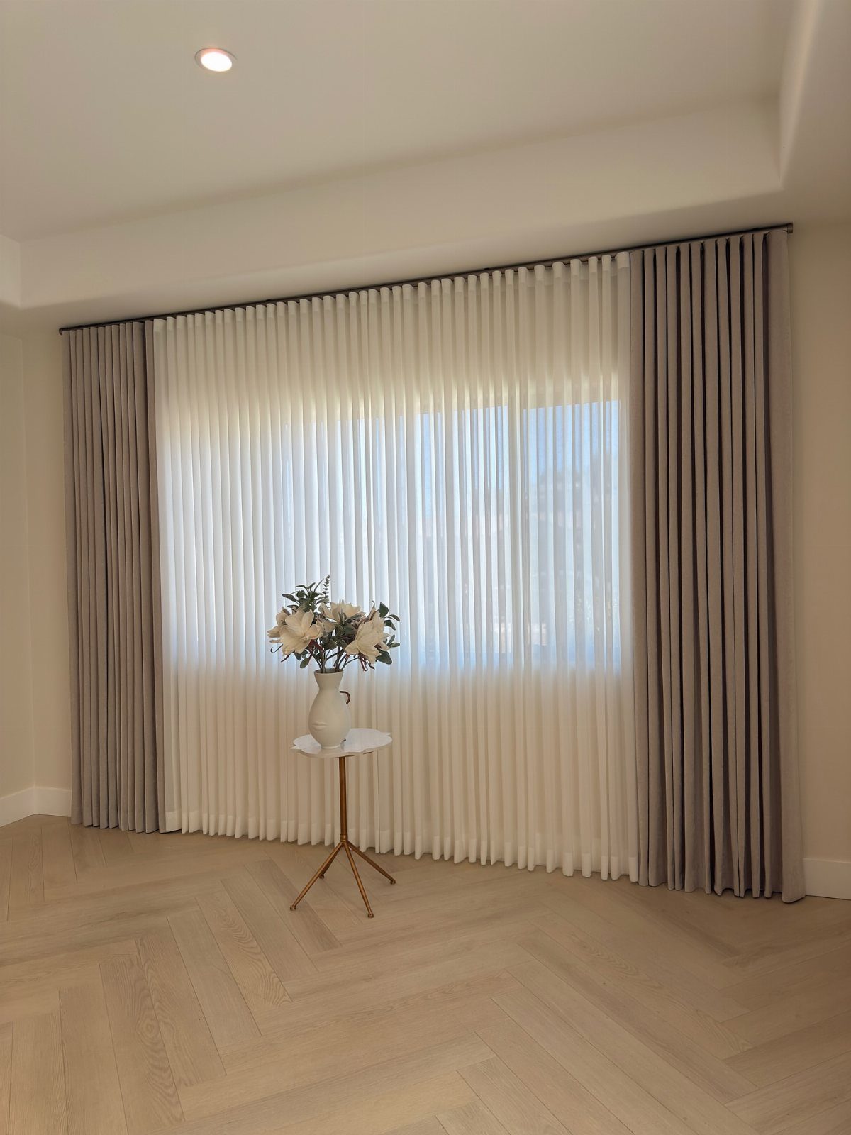 White sheer and grey opaque ripple-fold curtains in a bright living room.