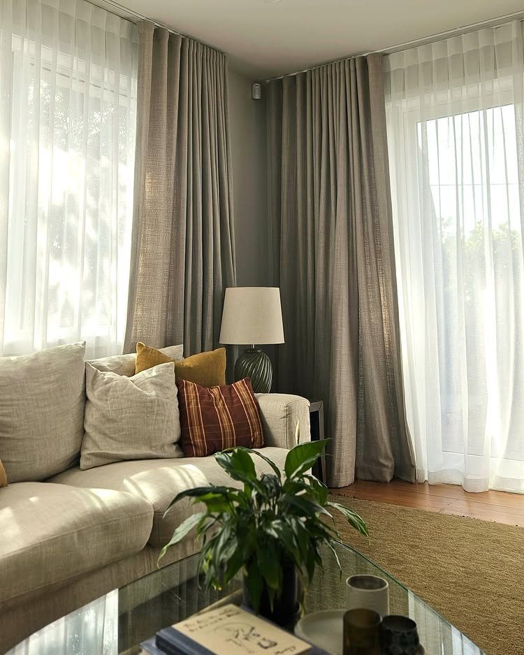 Layered taupe drapes and sheer white curtains in a bright, modern living room.