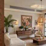 Modern living room with white sofa, wooden furniture, and a large framed painting.