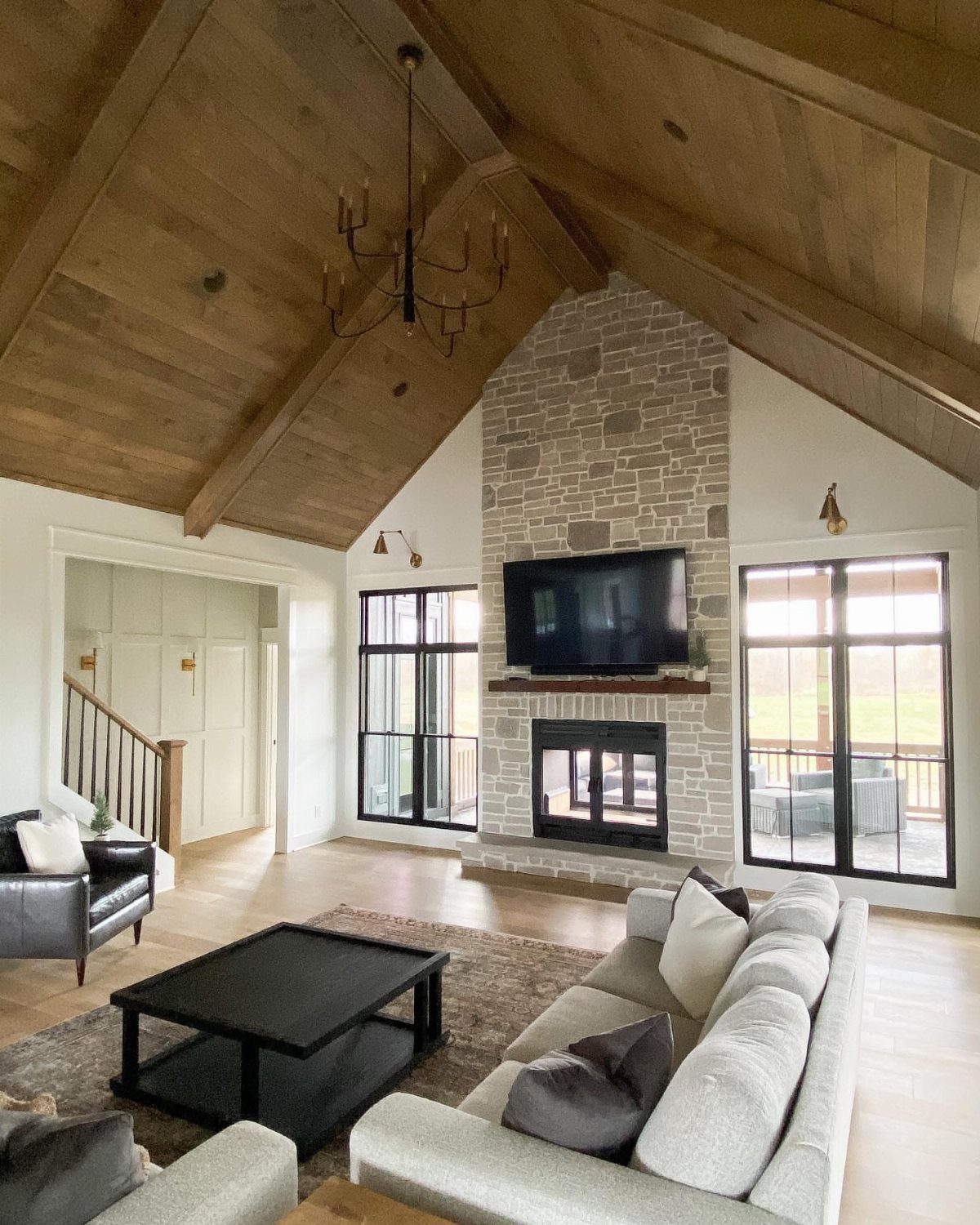 Living room with vaulted wood ceiling and stone fireplace with TV mounted above.