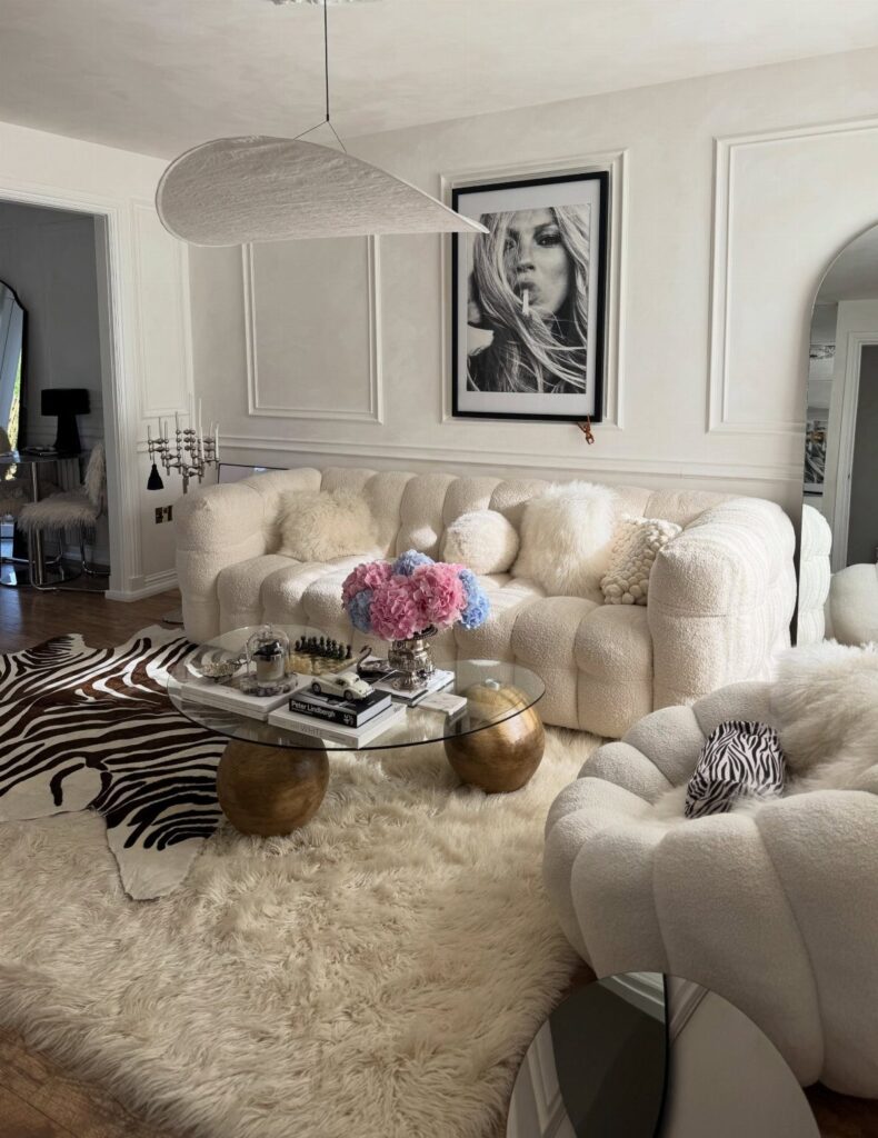 White cozy living room with plush furniture, shag rug, and zebra print accents.